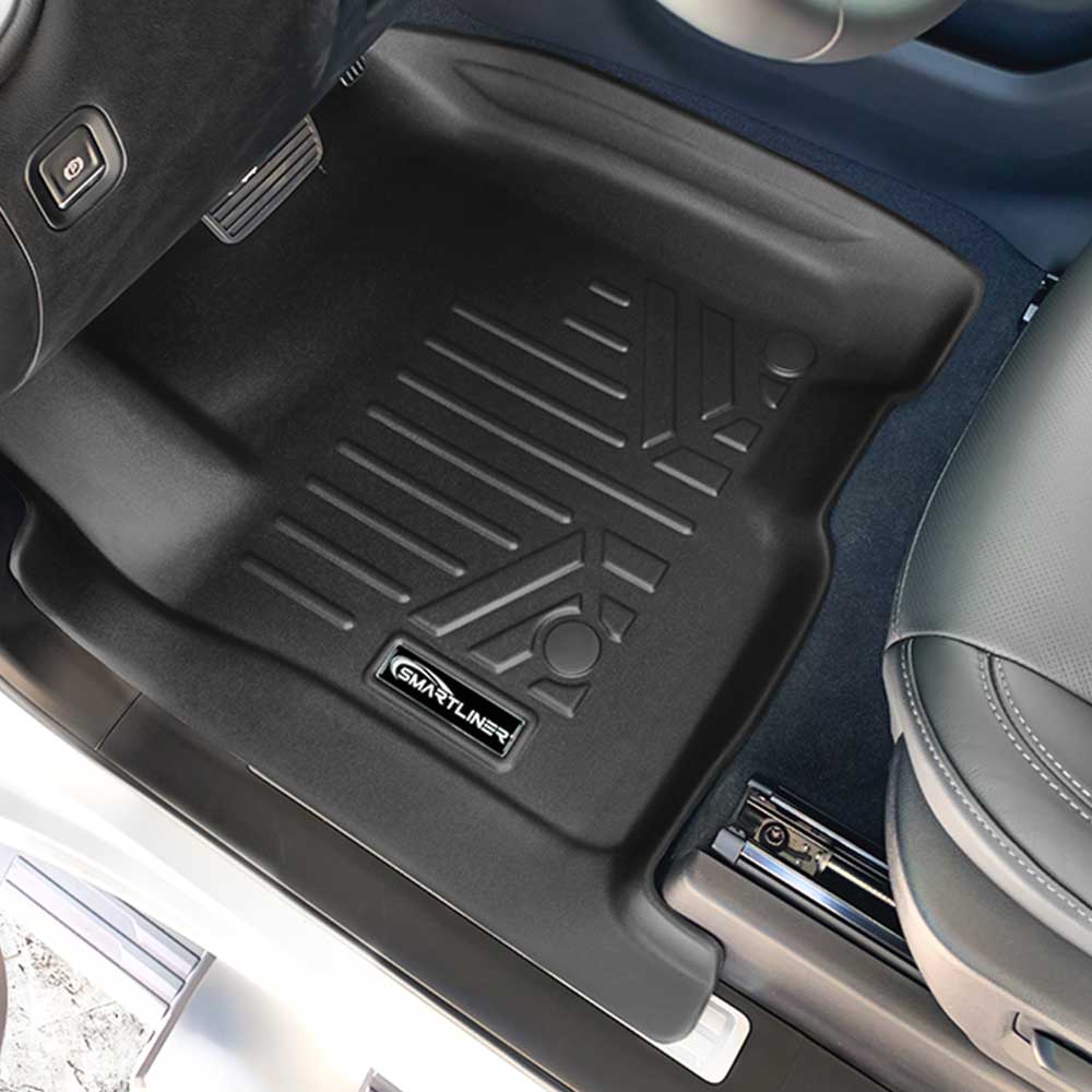 A black rubber car floor mat installed in a GMC Sierra 1500's footwell, shown from above. The mat has ribbed texture and a visible 'SMART LINER' brand patch near the bottom edge.
