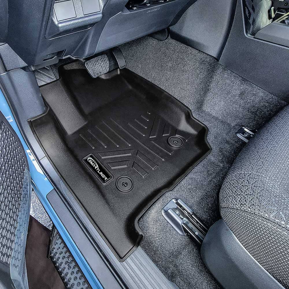 A black SmartLiner floor mat installed in a Toyota 4runner's footwell, shown from an overhead angle with the carpeted interior and seat visible.