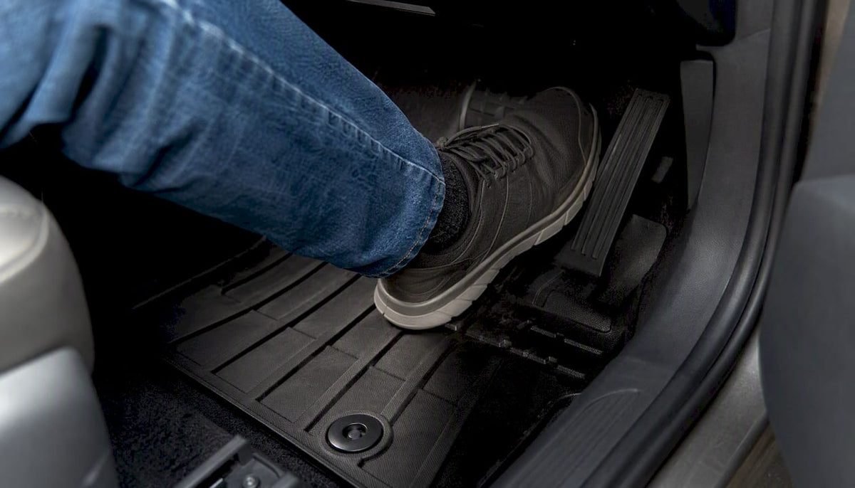 Driver's foot pressing brake pedal on secured floor mat