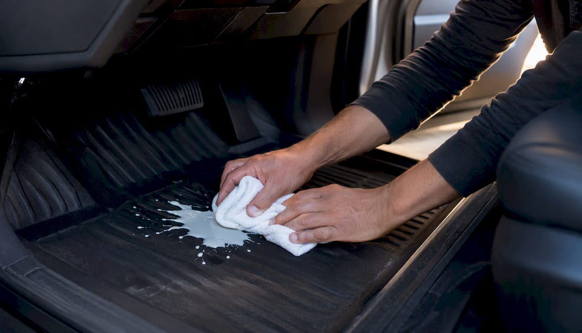 Hands blotting paint spill on car carpet