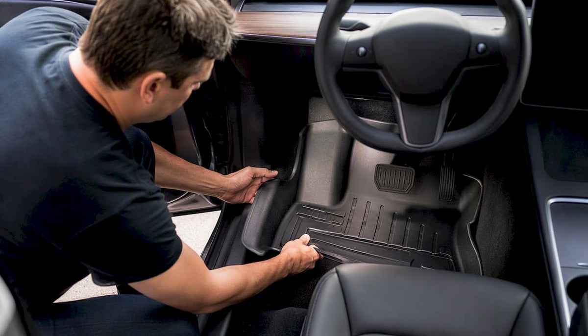 Hands installing custom floor mat in Tesla Model 3