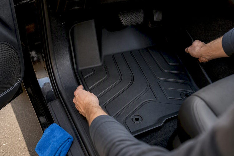 Hands installing a vehicle floor liner